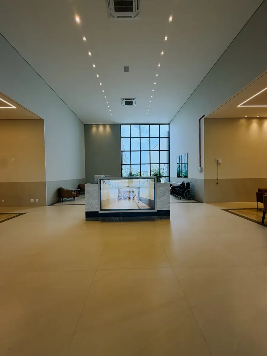 Hall de entrada do centro médico Aquarela Saúde, com pé-direito alto e janela envidraçada