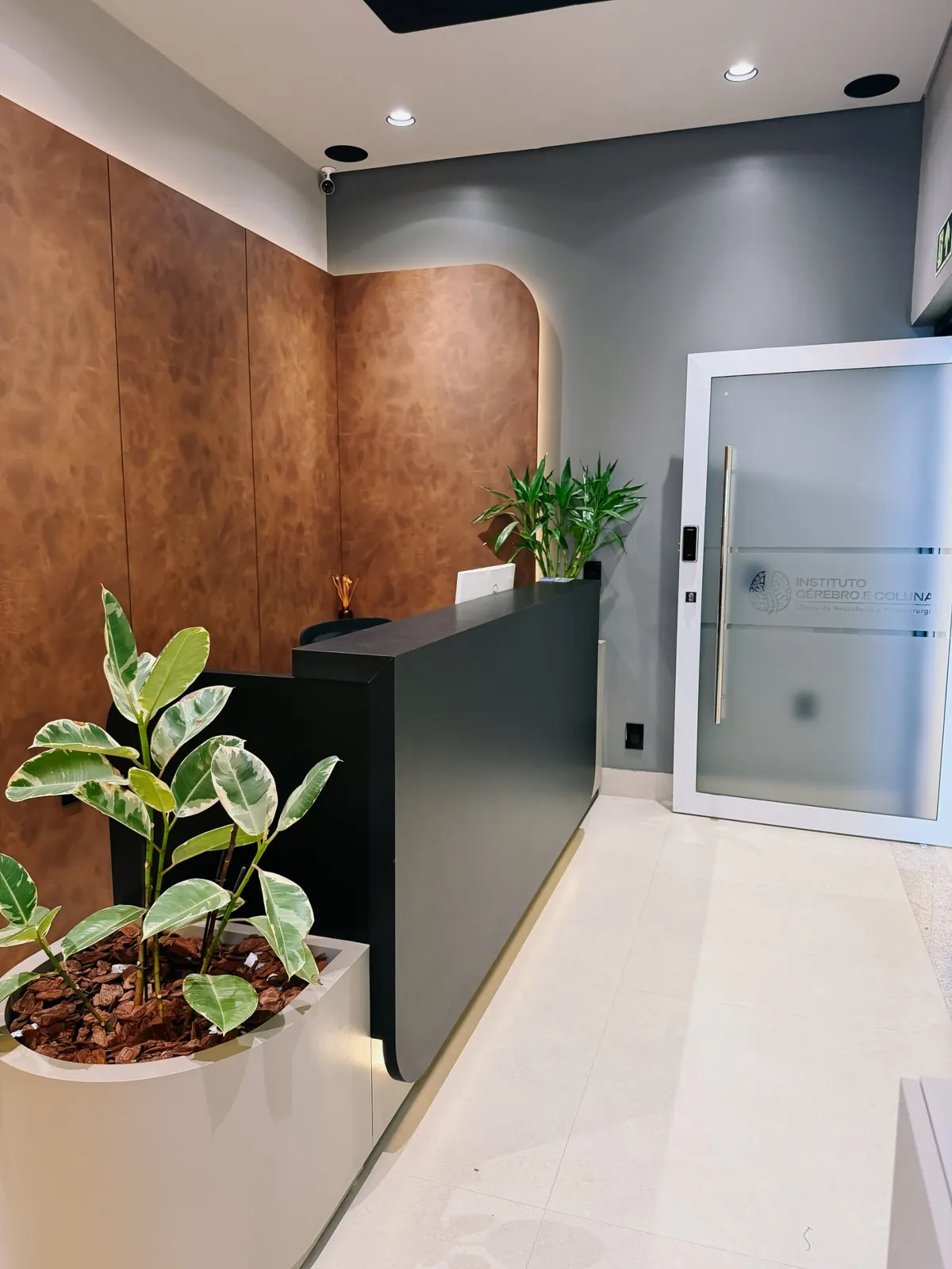 Recepção do Instituto Cérebro e Coluna, com parede em couro e porta com a marca do instituto